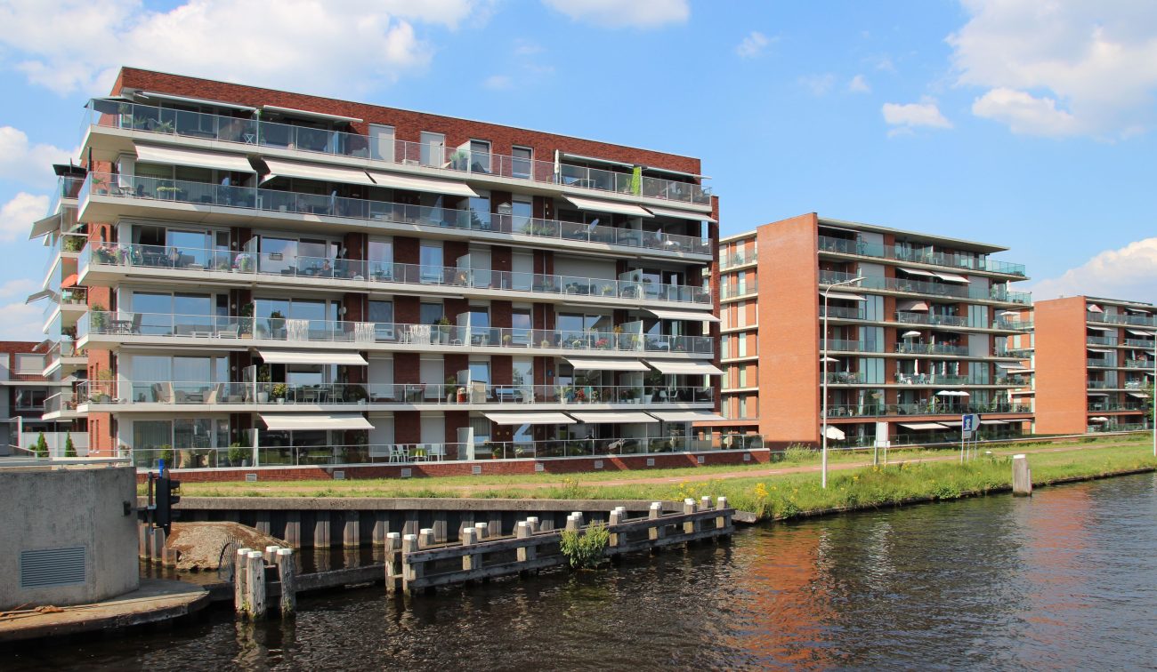 Nieuwbouwappartementen op het HIVA-terrein in Son, gezien vanaf het water, met zicht op de moderne gevel en de waterrijke omgeving.