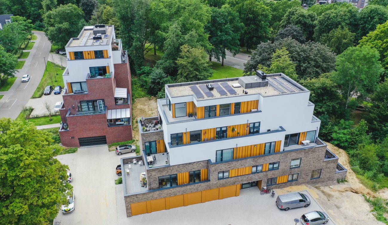 Modern woongebouw met dakterrassen, zonnepanelen en parkeerkoffer aan bosrand — Gebiedsontwikkeling Parkheuvel Heerlen