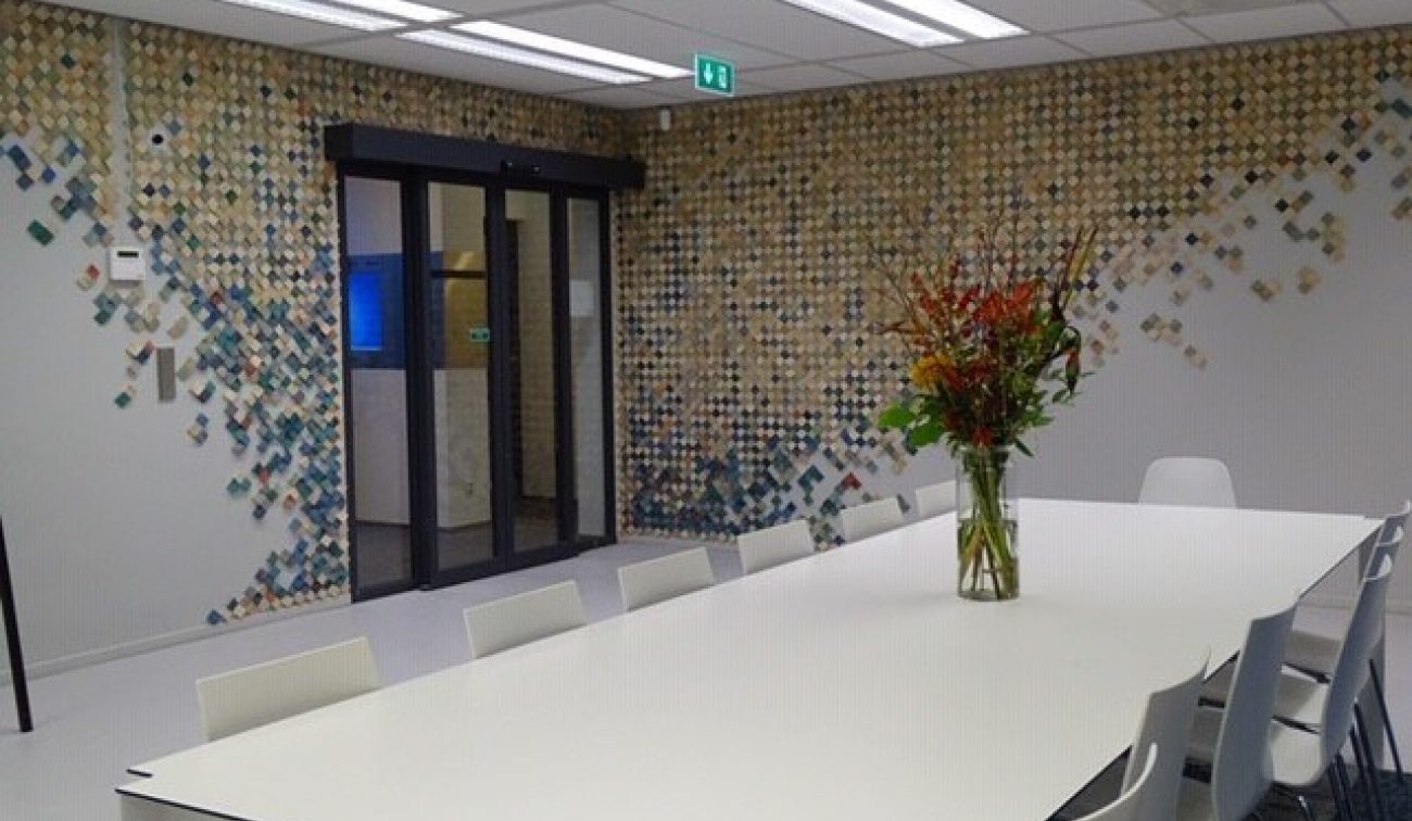 Meeting Plaza Utrecht: lichte zaal met witte vergadertafel, bloemenvaas en mozaïekwand in patronen