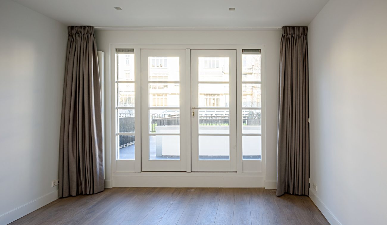 Lichte woonruimte met houten vloer, hoge ramen en tuindeuren naar terras – Ruysdaelstraat Amsterdam