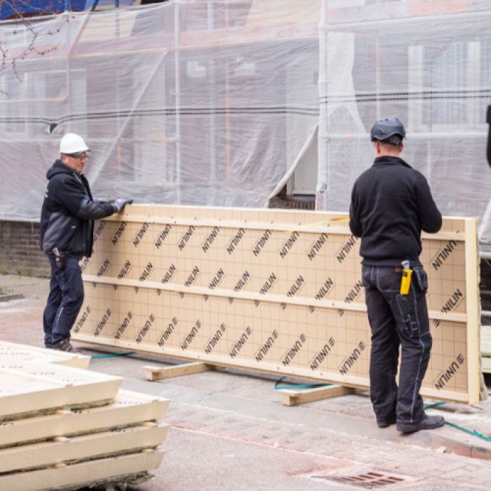 Monteurs verplaatsen geïsoleerde UNILIN panelen bij renovatie 91 woningen Maastricht.