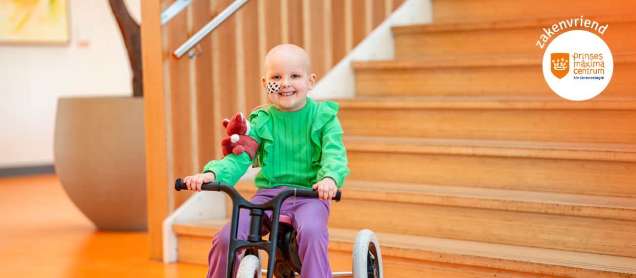 Een vrolijk lachend kind zit op een driewieler