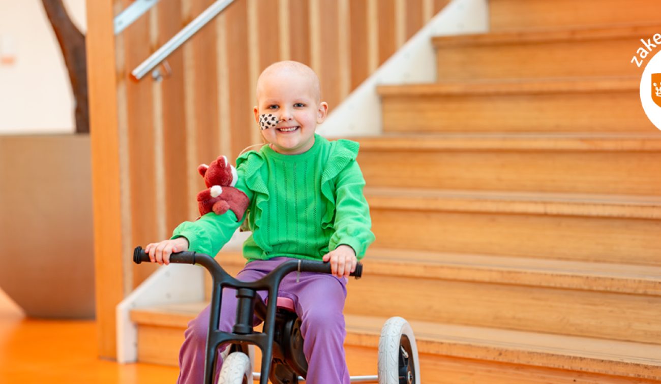 Een vrolijk lachend kind zit op een driewieler