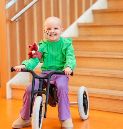 Een vrolijk lachend kind zit op een driewieler