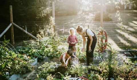Vouw met kinderen aan het werk in de moestuin