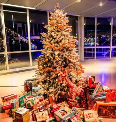 Een kerstboom met daaronder een grote stapel cadeaus