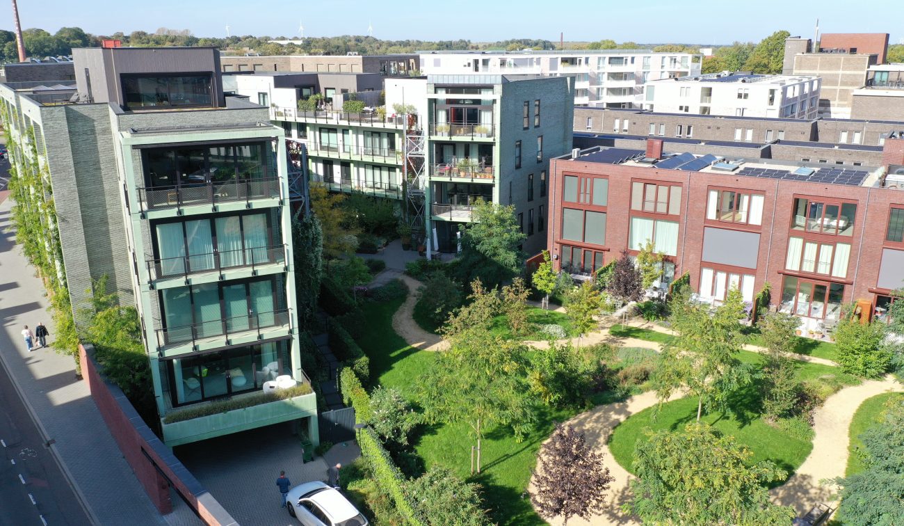 CPO Sphinx Maastricht – luchtfoto van groene binnentuin met slingerpaden en bomen, tussen groene en rode appartementengebouwen met balkons