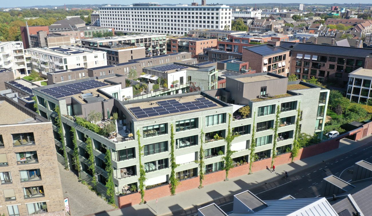 CPO Sphinx Maastricht – luchtfoto van appartementengebouw met groene gevel, klimplanten en zonnepanelen op daken in stedelijk blok