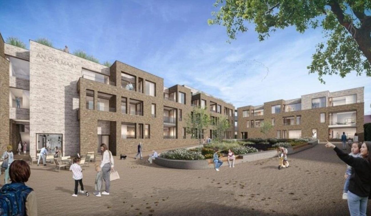 Impressie An d’r Maat Simpelveld: bakstenen woonblokken met balkons rond groen, pleintje met terrassen
