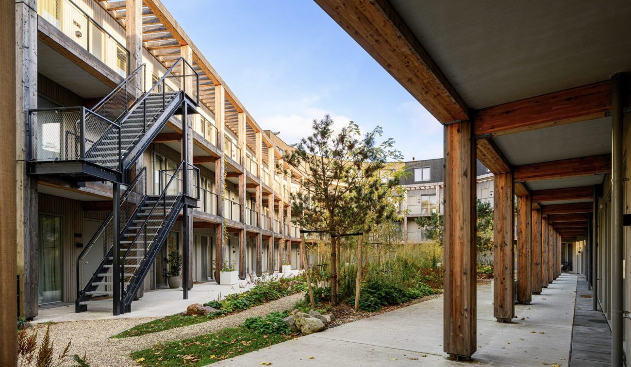 Nieuwbouw ROOT Eindhoven – duurzaam binnenhof met houten constructies, galerijen en groene natuurinclusieve tuin.