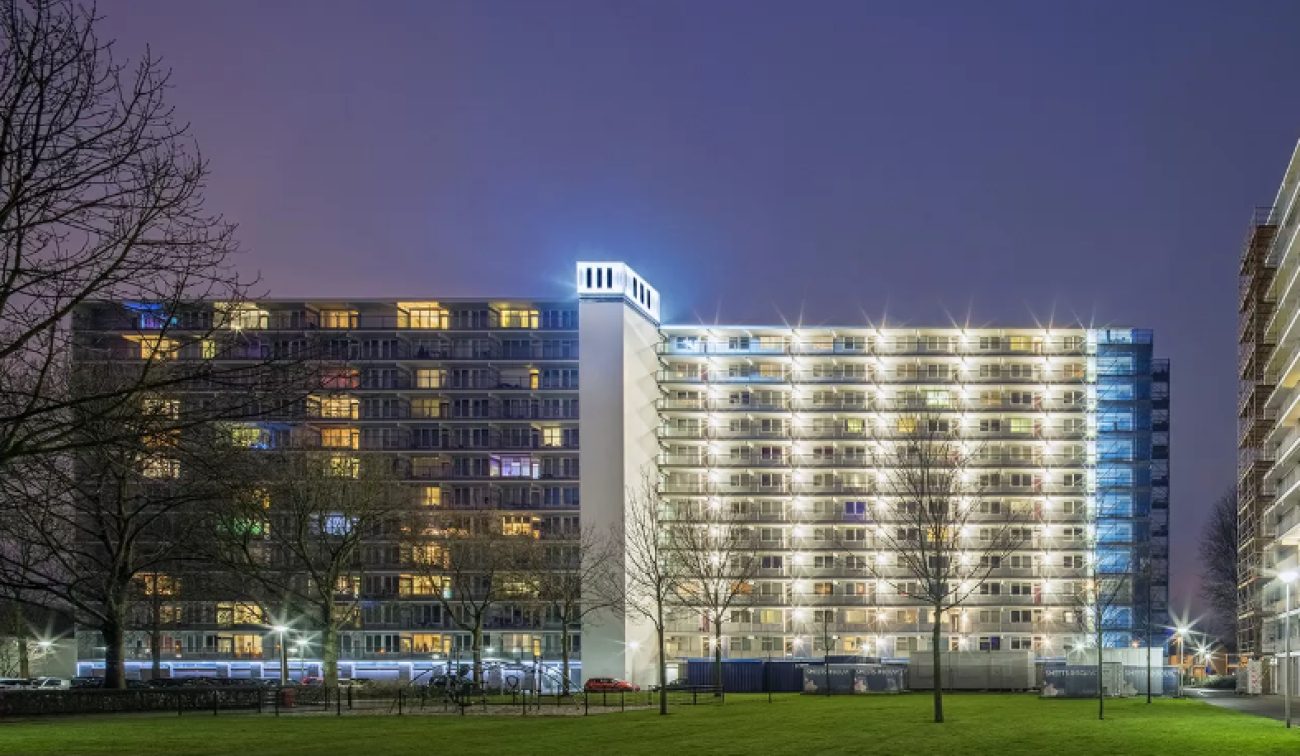Avondaanzicht galerijflats Heerlerbaan Heerlen met verlichte gevels en centraal trappenhuis