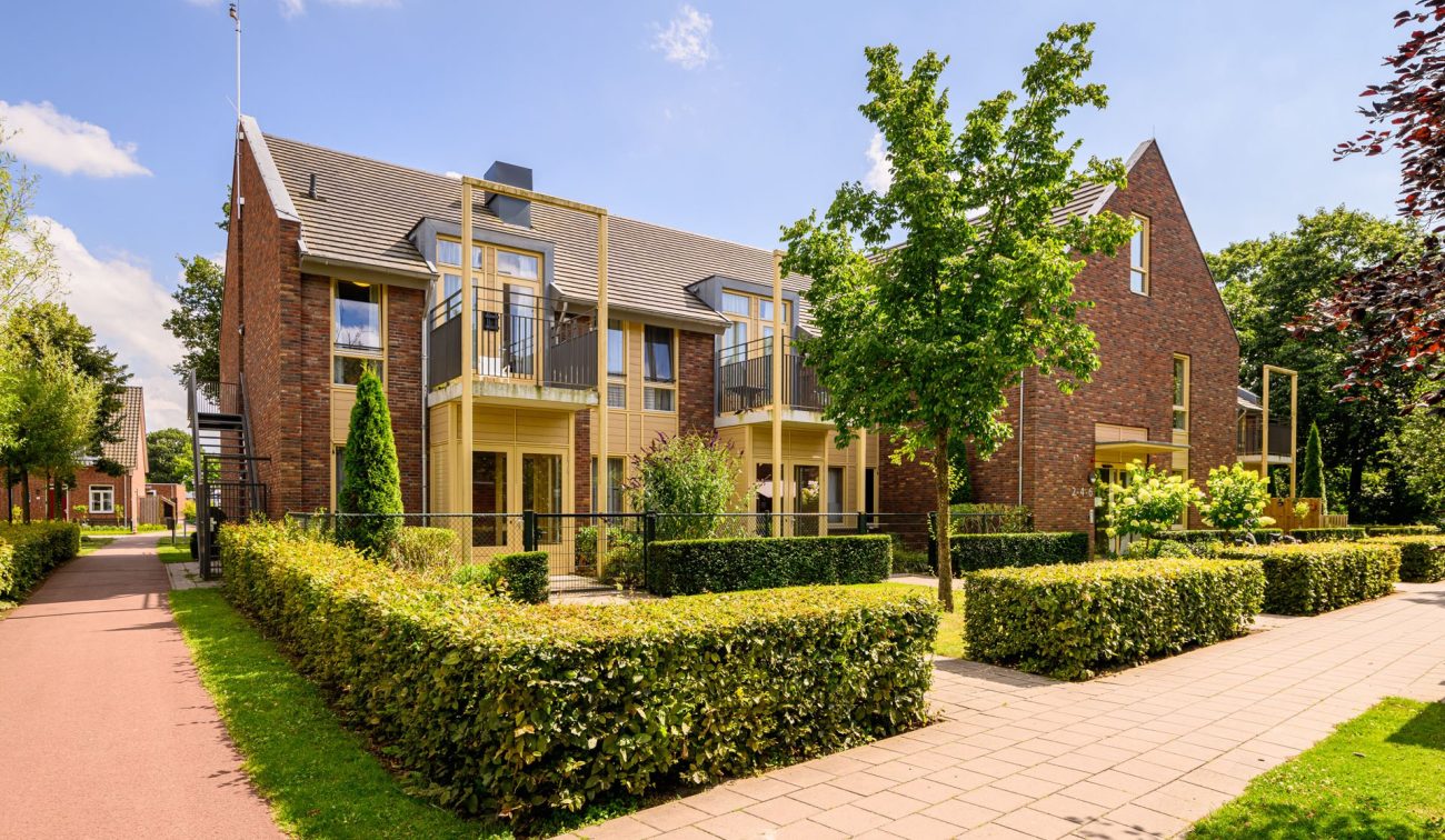 Nieuwbouwappartementen in Kloostervelden in Sterksel met bakstenen gevel, houten accenten, balkons en groene inrichting van de straat.