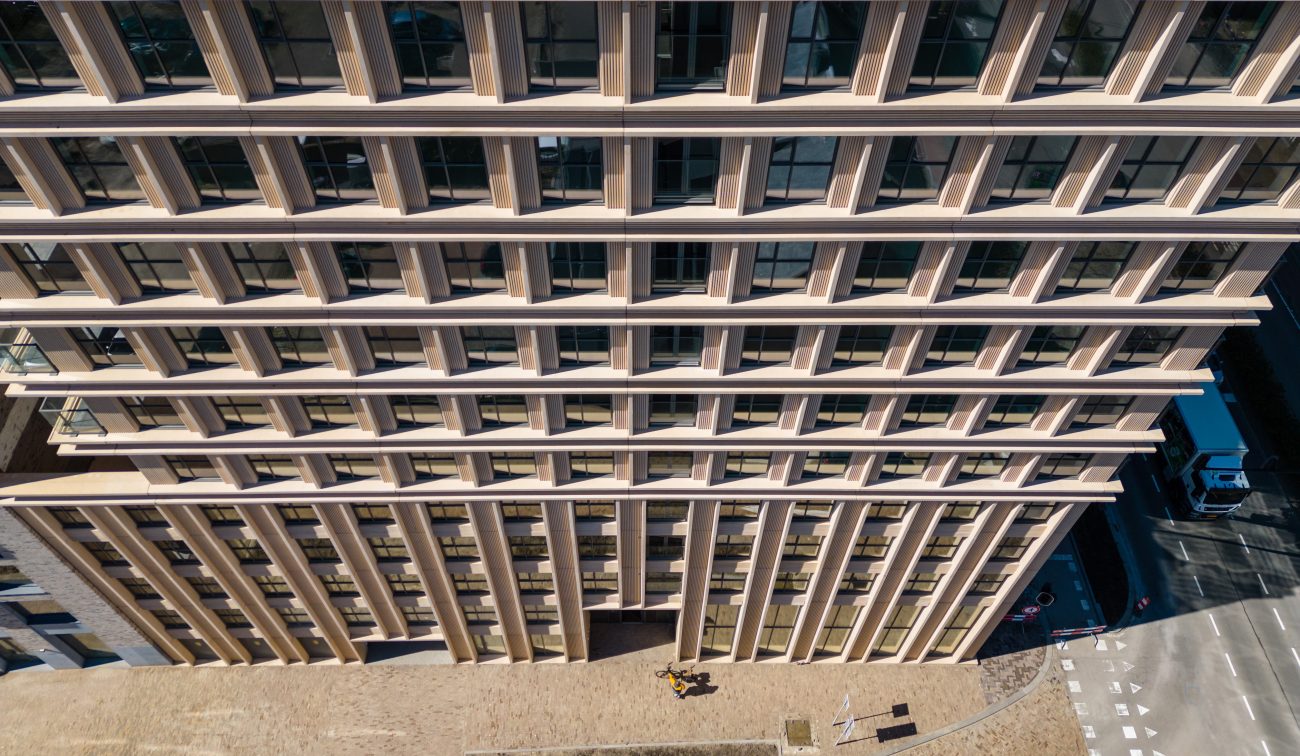 Ontwikkeling De Bankier Tilburg – vogelvluchtperspectief op de gevel met ritmische verticale lamellen, grote ramen en het straatplein aan de voet van de toren.