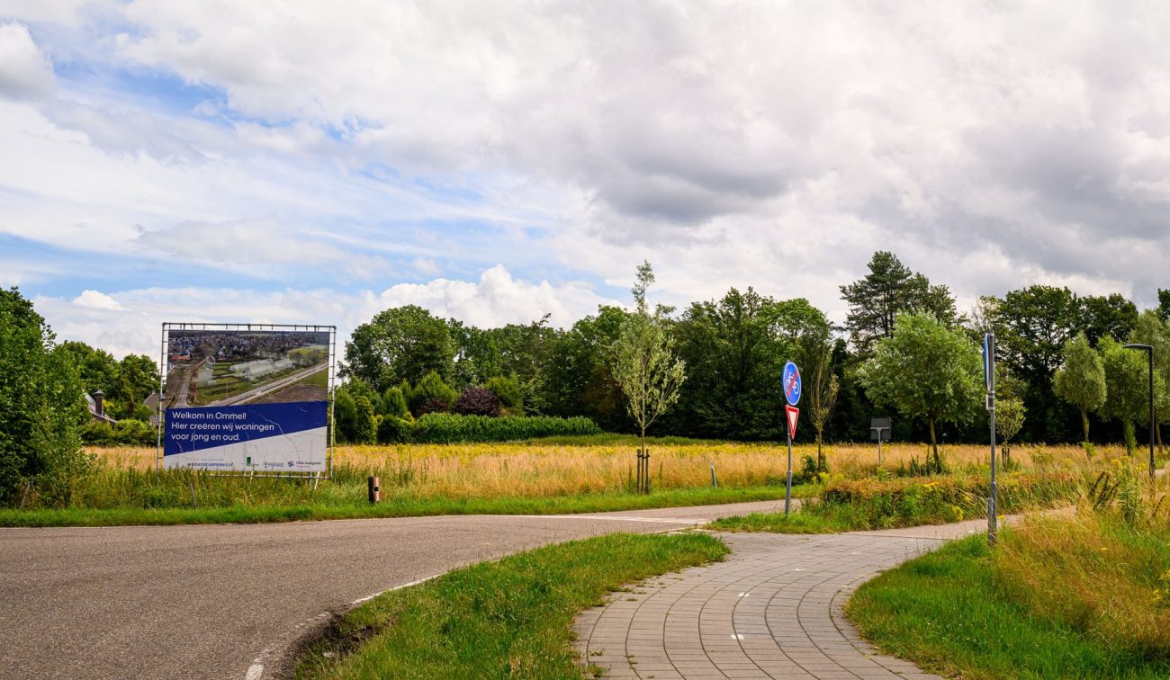 Toekomstige bouwlocatie aan rand van Ommel met aankondigingsbord en grasland — Ontwikkeling Kluisstraat Ommel
