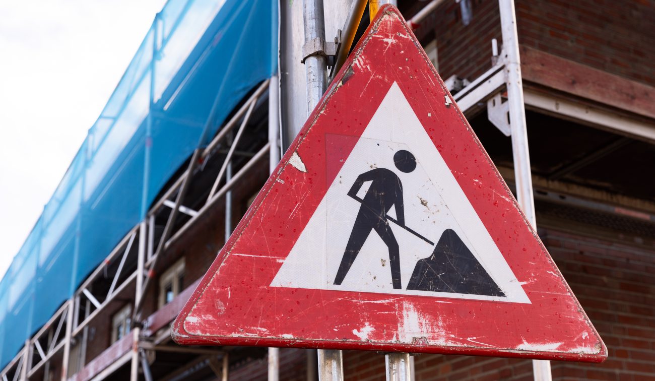 Waarschuwingsbord voor werkzaamheden bij woningen in steigers in Tuinzigt Haagpoort, vastgelegd tijdens het groot onderhoudsproject.