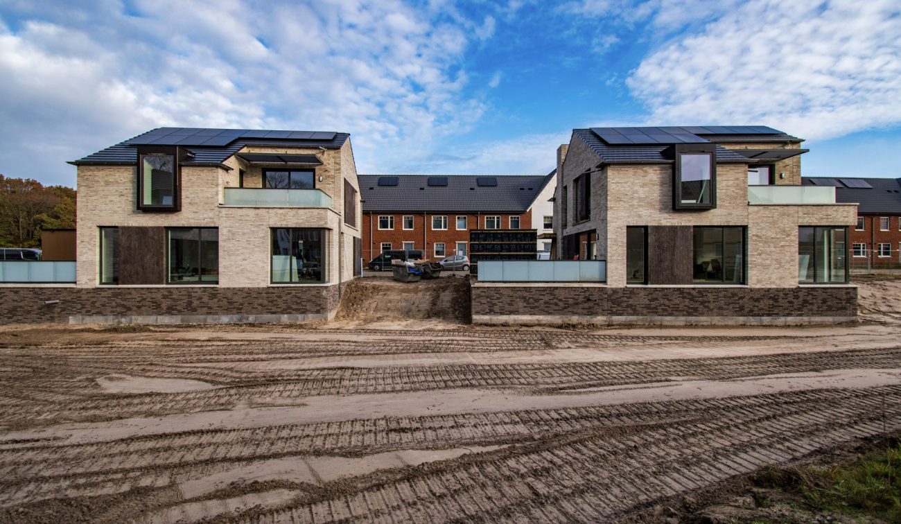 Beeld van twee moderne nieuwbouwwoningen met duurzame zonnepanelen in het project Wilhelminahaven in Oosterhout, in een bijna voltooide woonwijk.
