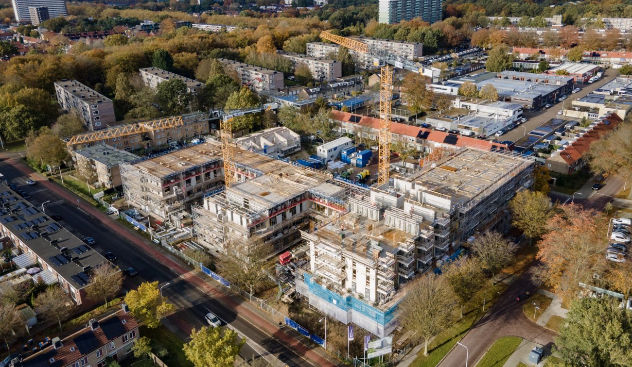 Luchtfoto van de bouw van woonzorgcentrum Zandstaete in Tilburg, met meerdere bouwkranen, steigers en omliggende woonwijken.