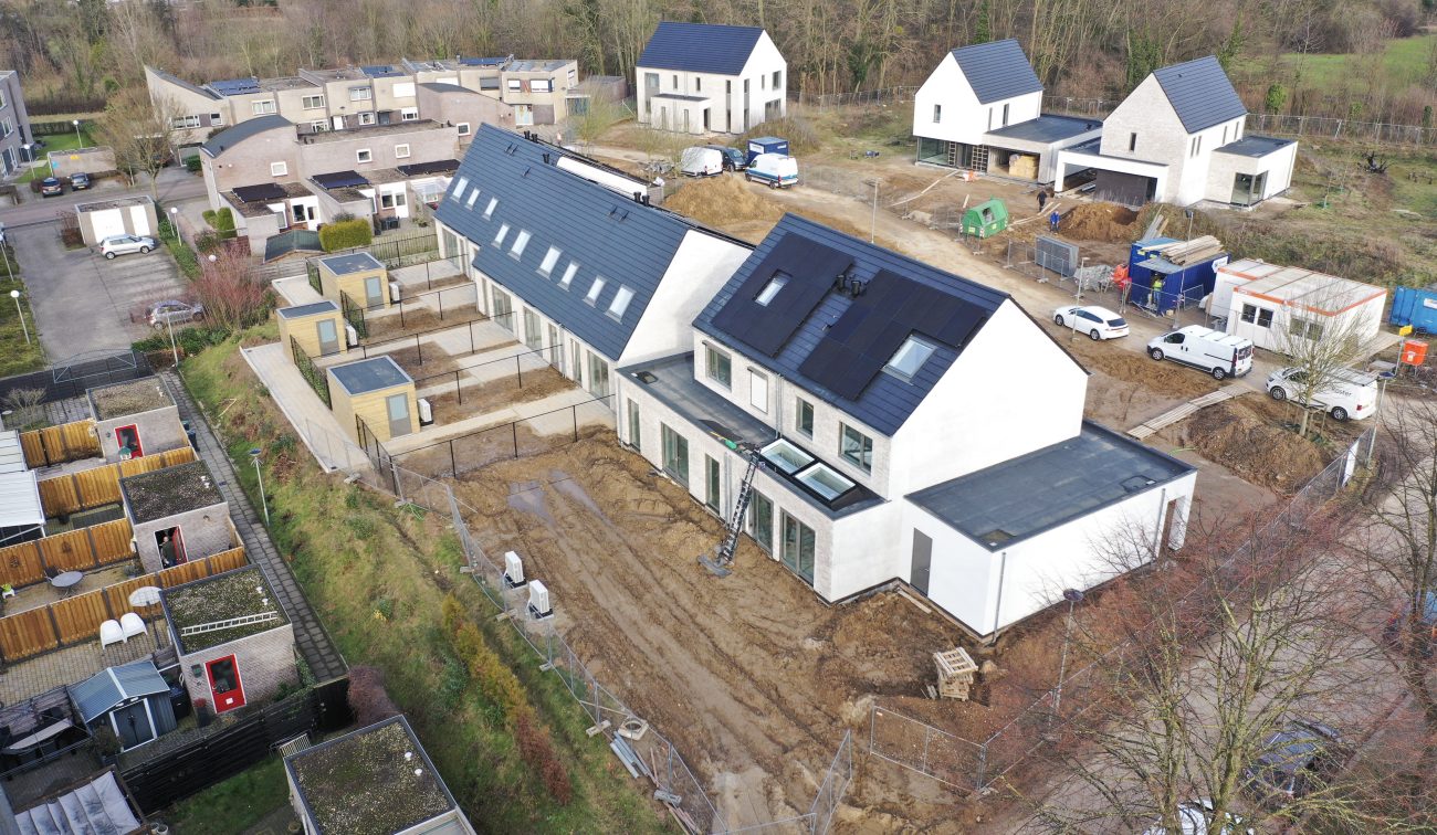 Nieuwbouw CPO Meerdel Elsloo – luchtfoto van witte eengezinswoningen met donker zadeldak en zonnepanelen, bouwterrein met tuinen in aanleg