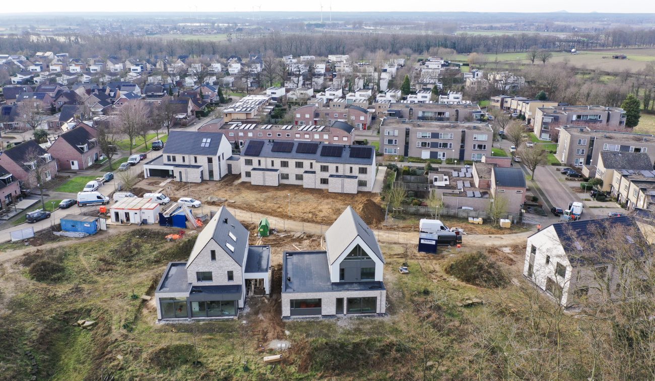 Nieuwbouw Elsloo – panorama bouwlocatie met twee vrijstaande huizen, rij nieuwbouwwoningen en bouwverkeer