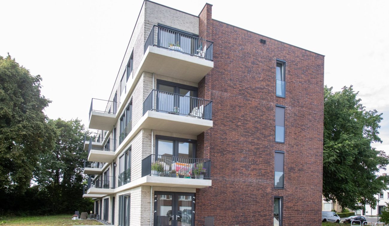 Hoekaanzicht nieuwbouw sociale huurappartementen Margraten met balkons en roodbruine zijgevel.