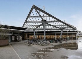 Fietsenstalling met stalen driehoekige dakconstructie en glazen overkapping bij gebouwentree