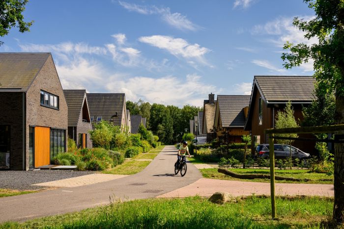 Nieuwbouwwoningen in Kloostervelden in Sterksel, met groene straten, moderne architectuur en een fietser op de weg.