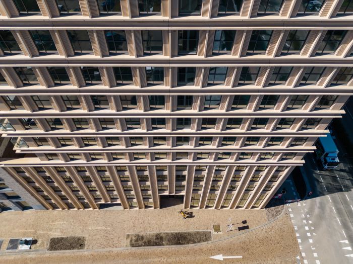 Ontwikkeling De Bankier Tilburg – vogelvluchtperspectief op de gevel met ritmische verticale lamellen, grote ramen en het straatplein aan de voet van de toren.