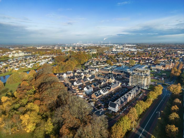 Luchtfoto van het voltooide nieuwbouwproject Wilhelminahaven in Oosterhout, met moderne appartementen en rijwoningen omringd door bomen en infrastructuur.