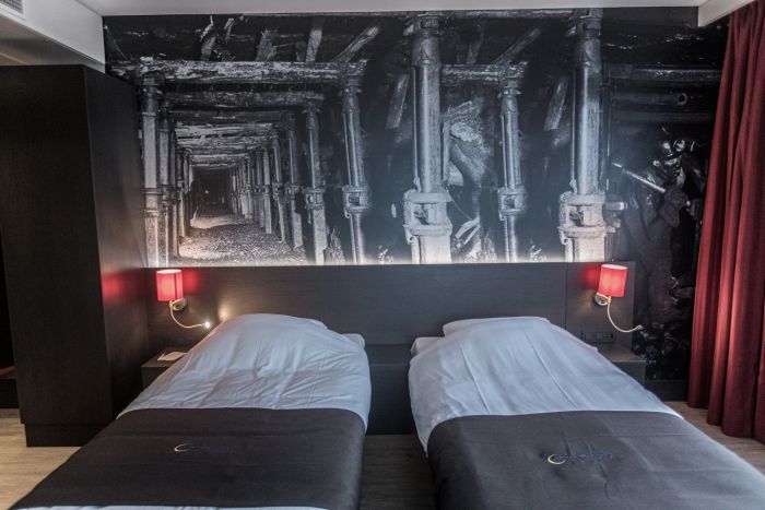 Interieur hotelkamer Geleen – twinbed opstelling met industriële muurprint en rode lampen